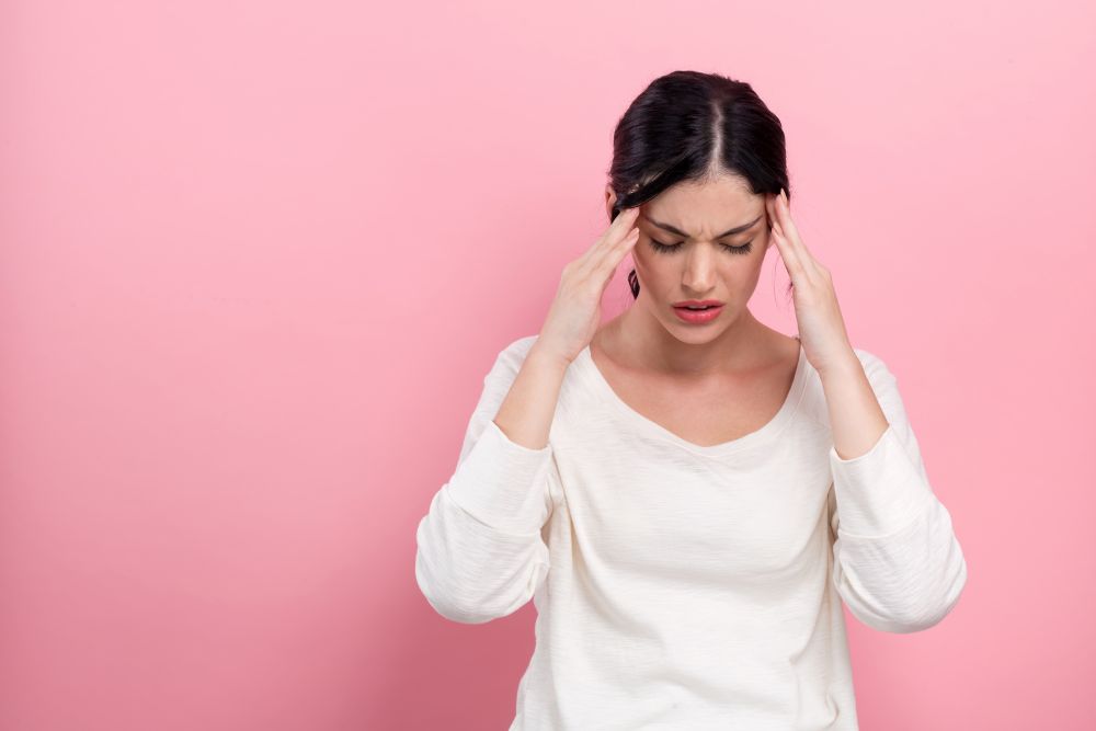 Woman massaging temples with essential oils during migraine