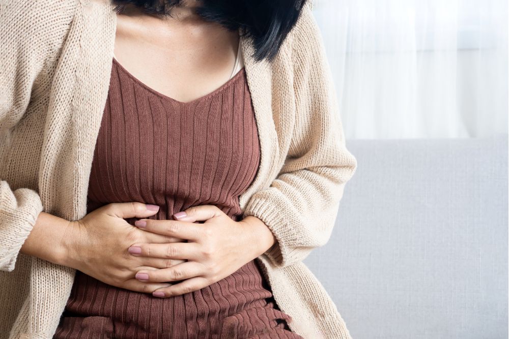 Unpleasant feeling in the stomach area – illustrative photo of a woman suffering from bloating and digestive discomfort