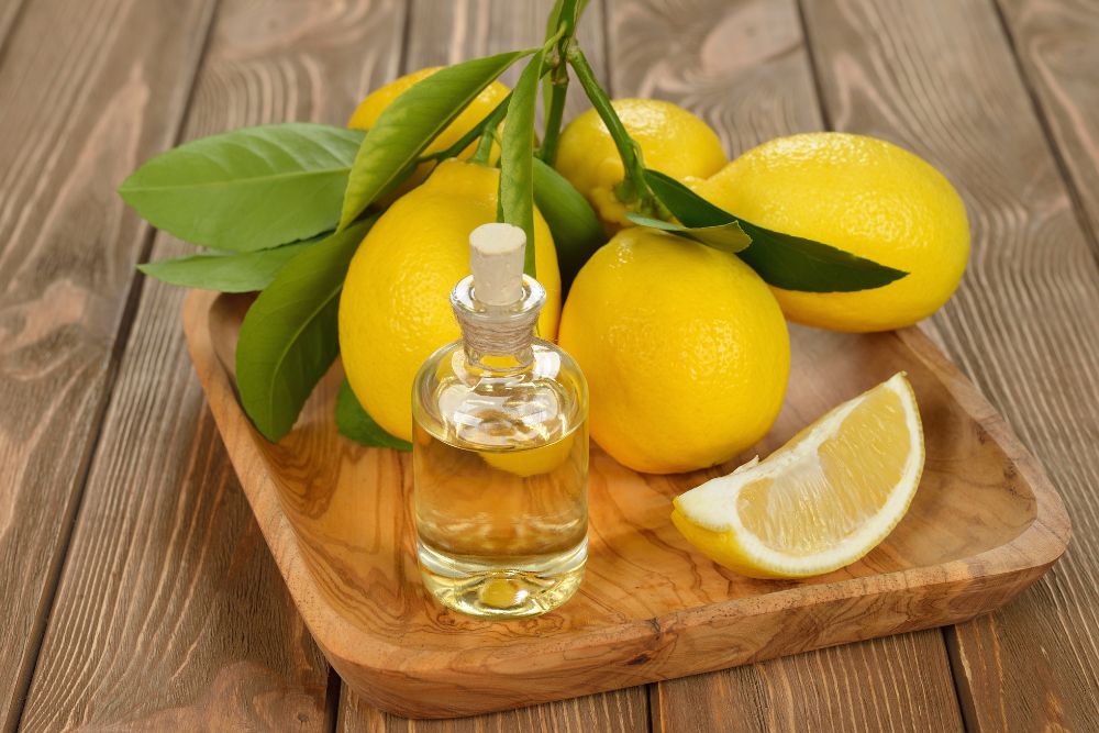 Citronový olej v malé lahvičce s čerstvými citrony na dřevěném podkladu