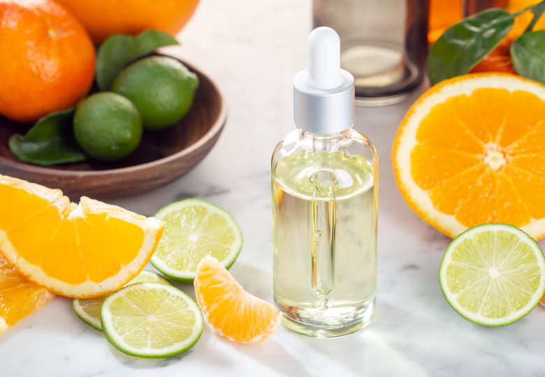 Lahvička s citronovým esenciálním olejem mezi čerstvými plátky citrusů – přírodní prostředek pro úklid bez chemie.